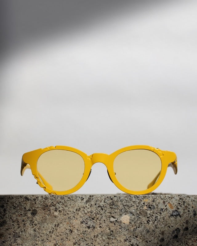 Titanium Museum frame in yellow with yellow lenses on a stone block